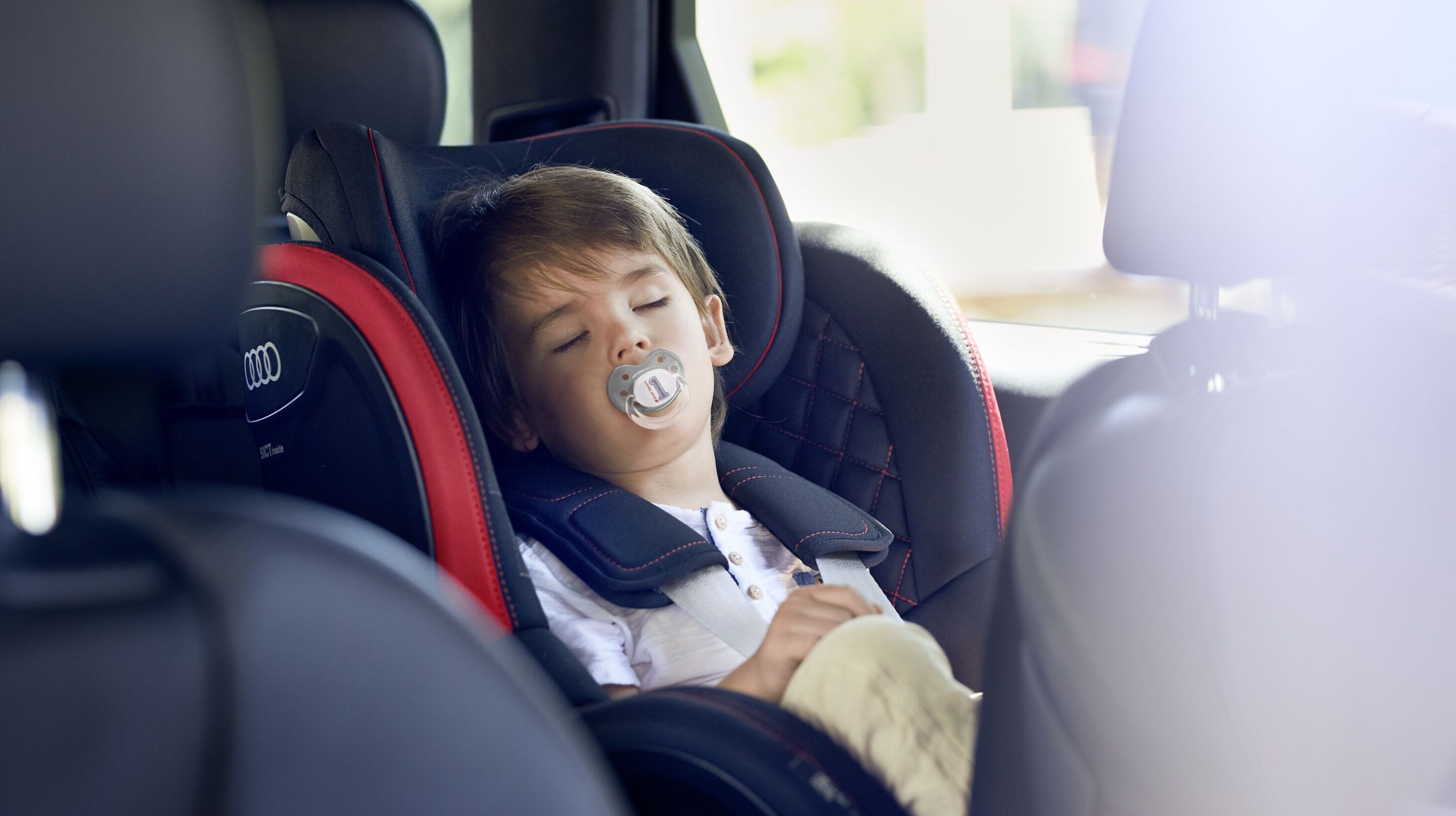 Ein kleiner Junge schläft in einem Audi Kindersitz