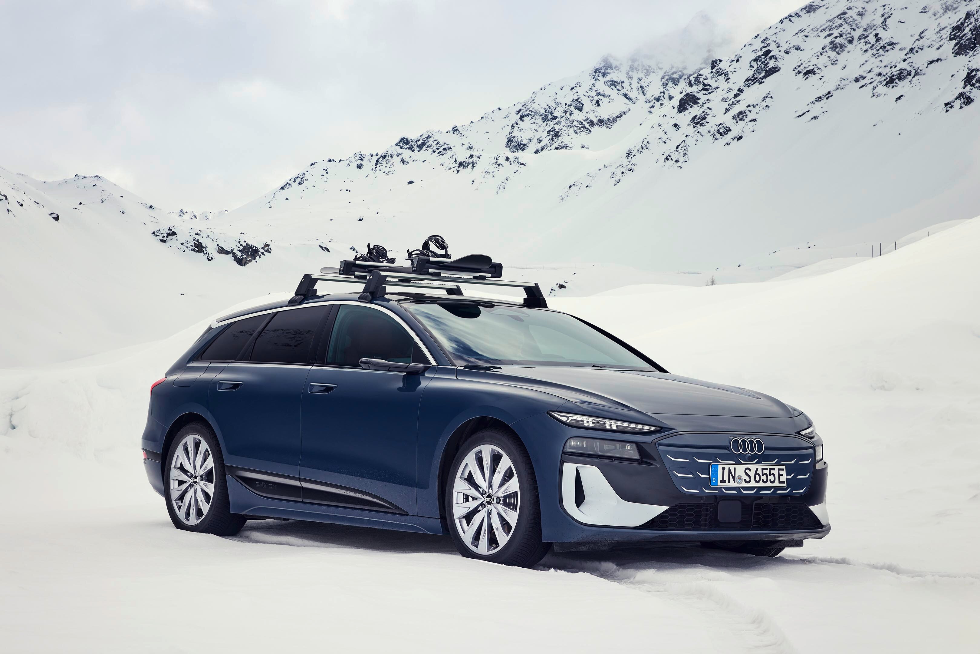 Ein Man zieht sich Skischuhe in einem roten Audi an, eine Frau mit Skiern steht davor