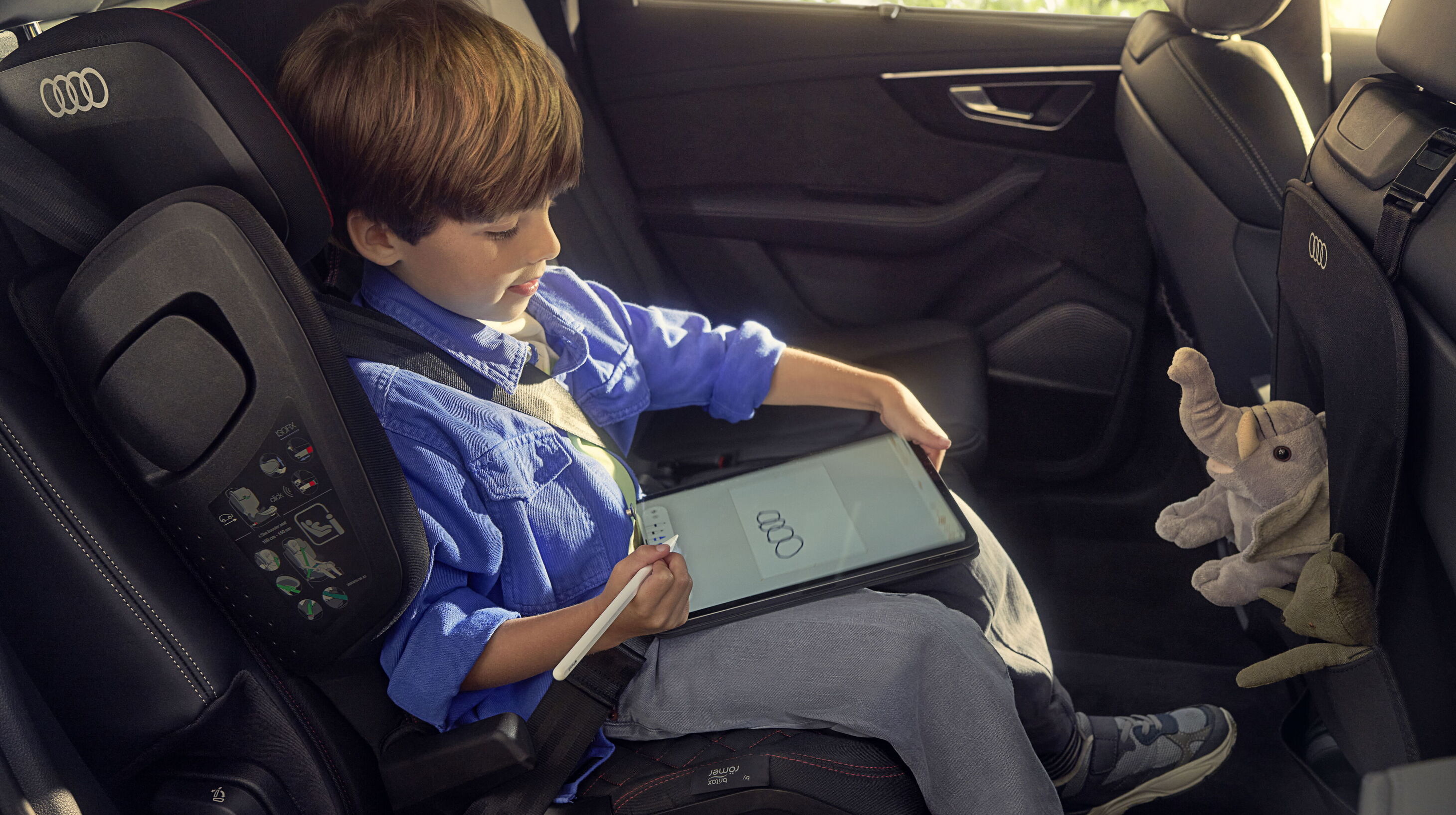Ein Kind sitzt spielend in einem Audi Kindersitz