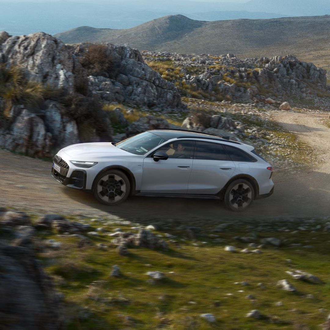 Audi A6 allroad e-hybrid se pelje po strmi makadamski cesti v skalnatem okolju.