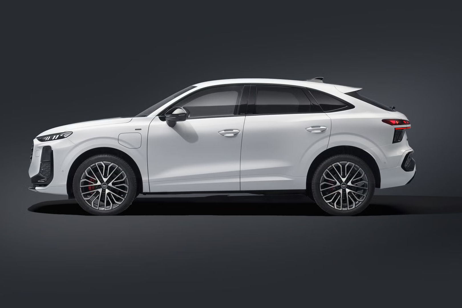 Seitliche Ansicht des Q3 Sportback e‑hybrid in dunkler Umgebung.