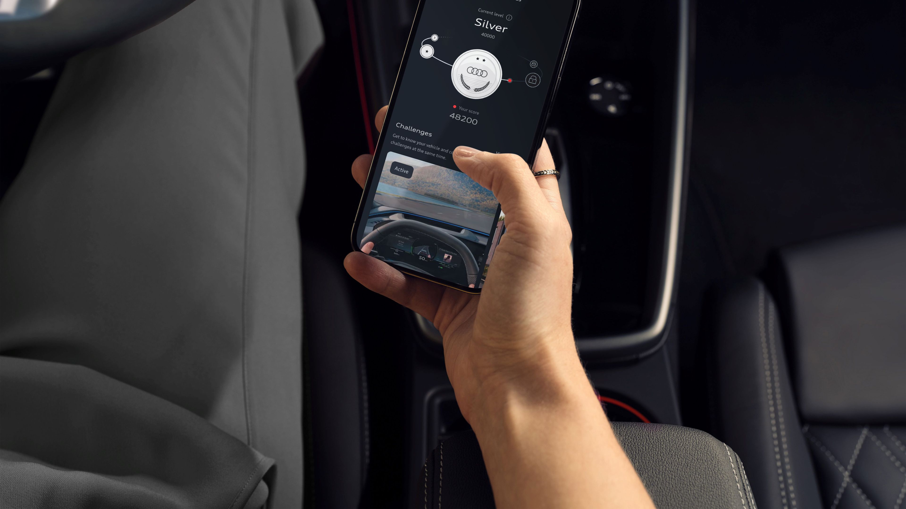 Oseba sedi na voznikovem sedežu Audi A3 in drži pametni telefon z odprto aplikacijo myAudi, povezano z vozilom. Na zaslonu so prikazane informacije o avtomobilu. Okolica prikazuje eleganten, temen in digitalen interier avtomobila z vidnim volanom in armaturno ploščo.