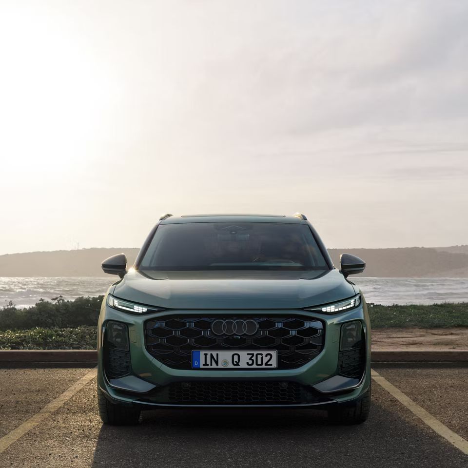 Audi Q3 SUV s sprednje strani, parkiran ob jezeru.