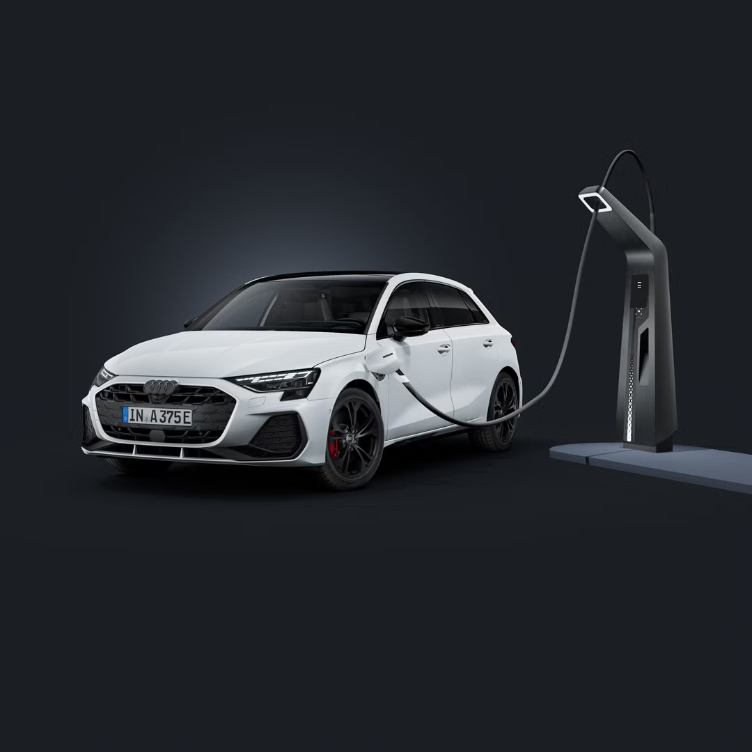Audi A3 Sportback TFSI e, fotografiran iz sprednjega bočnega kota na temnem studijskem ozadju, z LED-žarometi, črnimi športnimi platišči in priključkom za polnjenje na sprednjem levem blatniku.