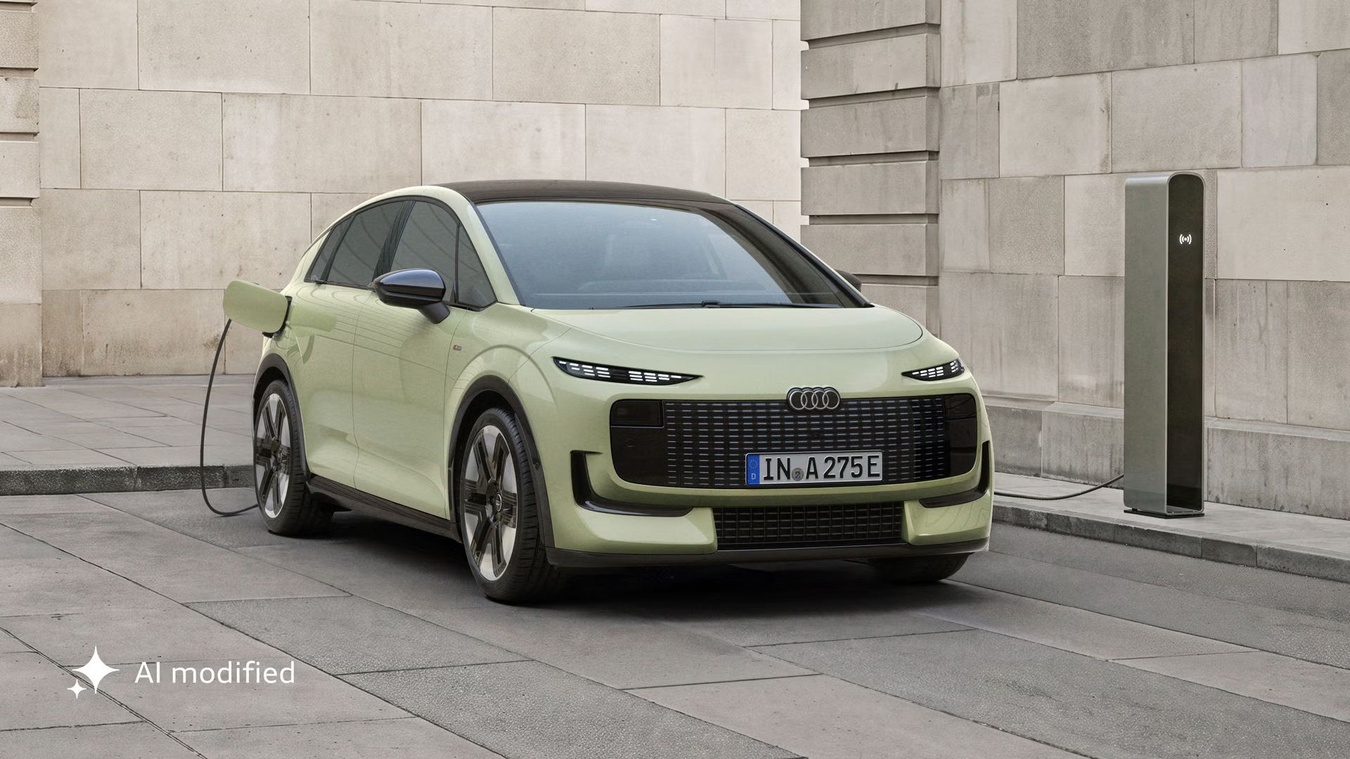 Der Audi A2 e-tron, frontal von hinten fotografiert, parkt vor einem modernen Gebäude. Das Fahrzeug ist an eine Ladesäule angeschlossen.