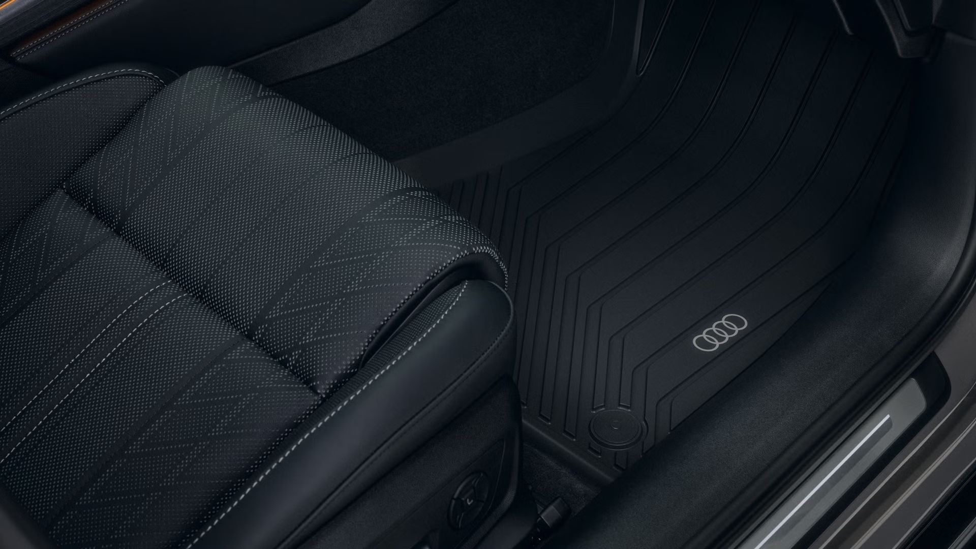 Bližnji posnetek prostora za noge na sovoznikovi strani vozila Audi A6 allroad s podlogo, ki je odporna na vse vremenske razmere.