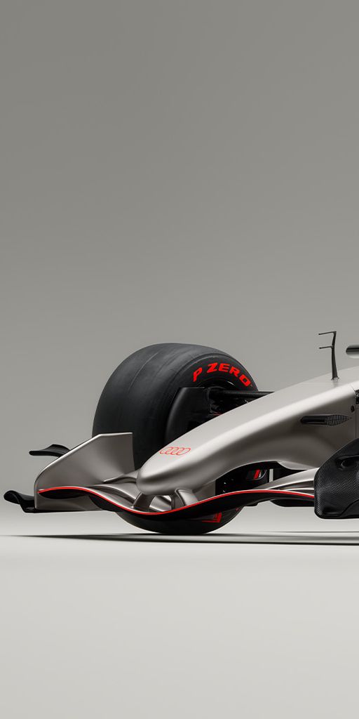 Audi F1®, osvetljen z leve strani, z aerodinamično oblikovano karoserijo in rdečimi trakovi na kolesih. 