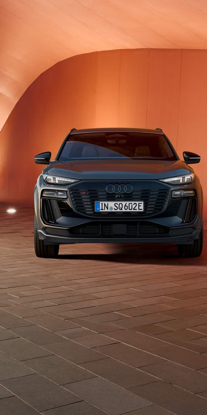 Audi SQ6 parkiran pred opečnato rdečim zidom