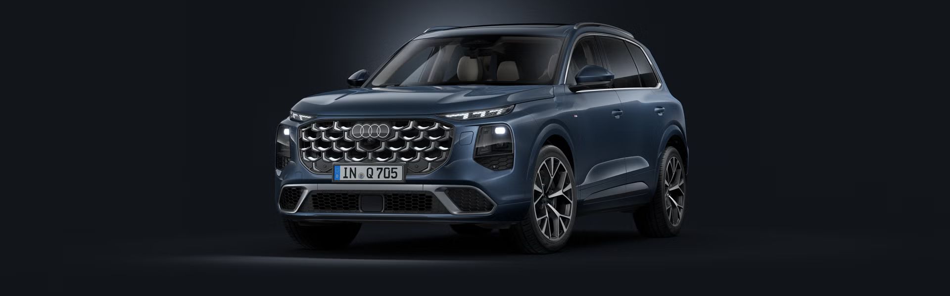 Poševen pogled spredaj na Audi Q7 SUV na temnem ozadju.