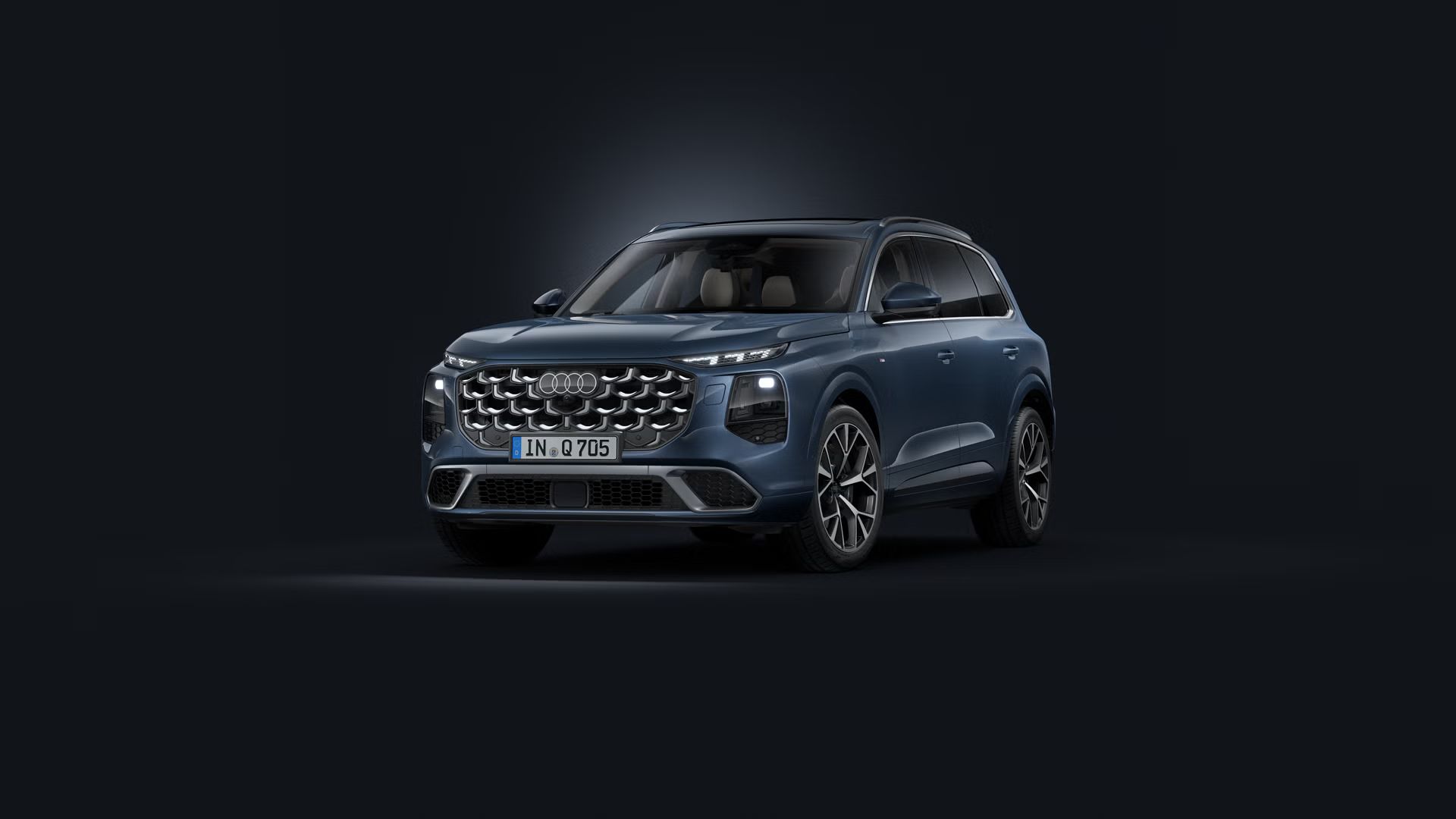 Poševen pogled spredaj na Audi Q7 SUV na temnem ozadju.
