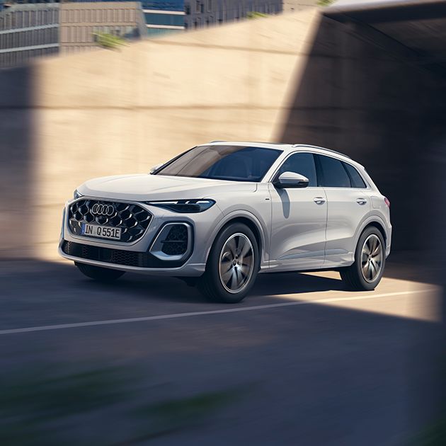 Audi Q5 SUV e-hybrid vozi skozi sodoben betonski tunel. 