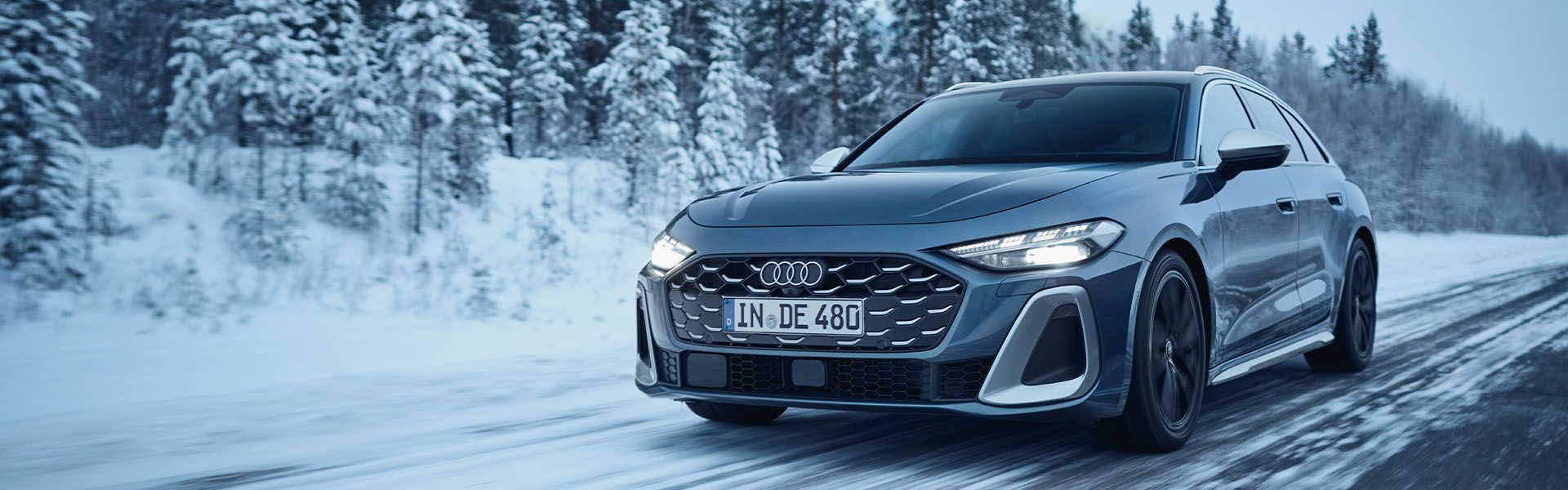 Športni avtomobil Audi S5 vozi po zasneženi cesti obdan s snežno pokrajino.  