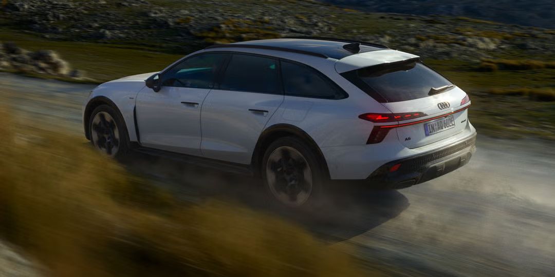 Audi A6 allroad e‑hybrid, prikazan s strani, pri polni hitrosti na gorski cesti.