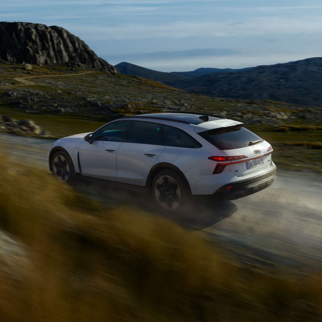 Audi A6 allroad e‑hybrid, prikazan s strani, pri polni hitrosti na gorski cesti.
