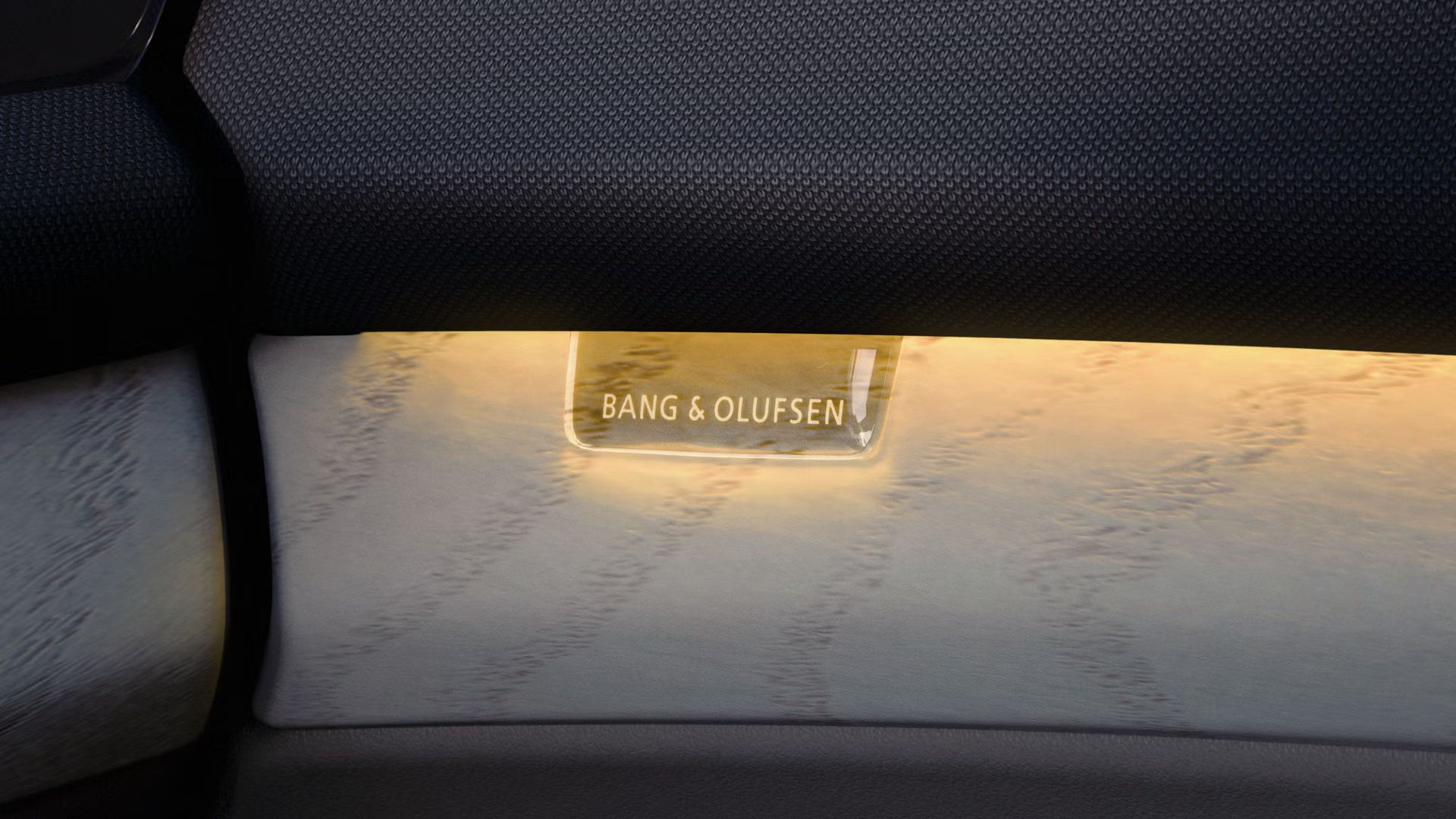 Osvetljen detajl notranjosti Audi Q9 SUV z napisom Bang & Olufsen in ambientalno osvetlitvijo.