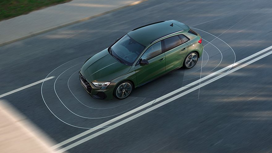 Audi A3 Sportback vozi po dvopasovni cesti, viden iz ptičje perspektive. Prilagodljiva asistenca za hitrost vam med vožnjo v vašem vozilu Audi nenehno  pomaga vzdrževati hitrost in potrebno razdaljo do spredaj vozečega vozila.