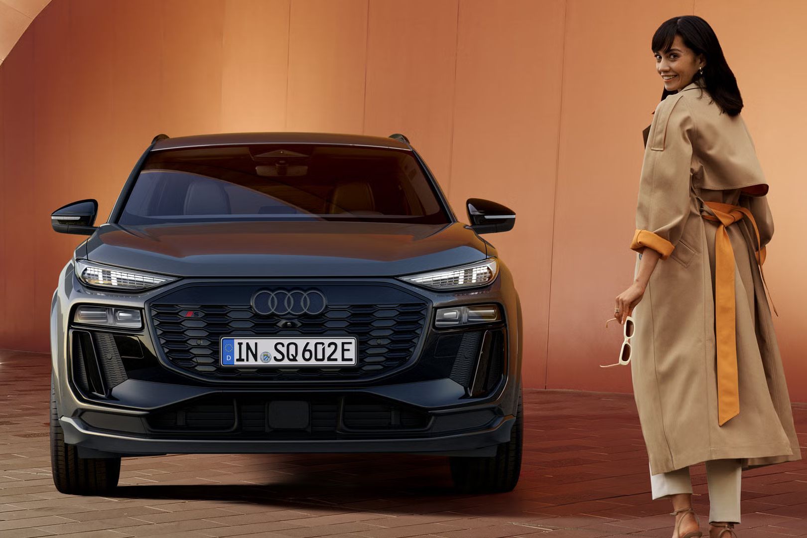 Audi SQ6 parkiran pred opečnato rdečim zidom