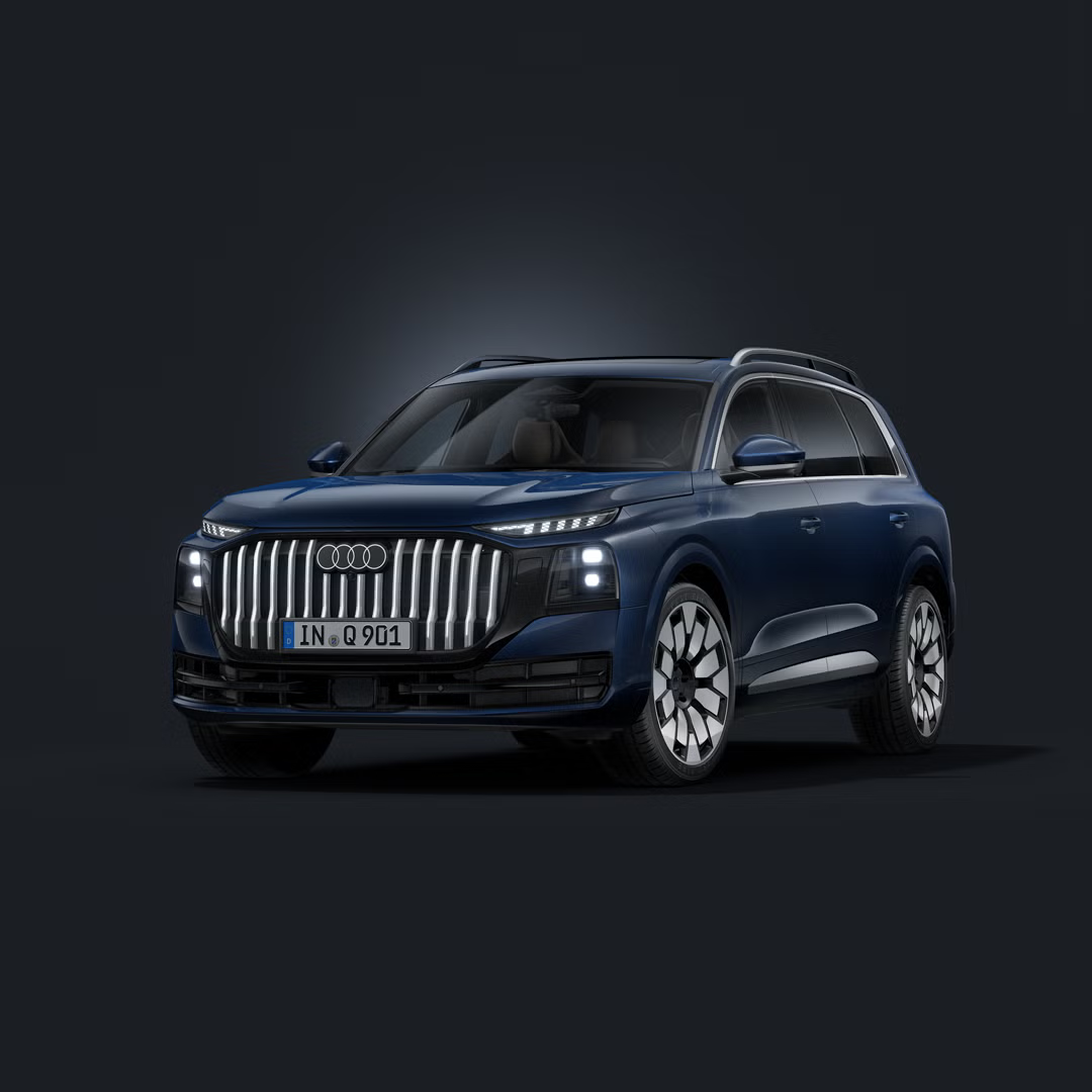 Temno moder Audi Q9 SUV, fotografiran iz sprednjega bočnega kota na temnem studijskem ozadju, z markantno enodelno masko hladilnika, LED-žarometi in velikimi aluminijastimi platišči.