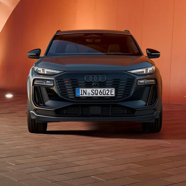 Audi SQ6 parkiran pred opečnato rdečim zidom