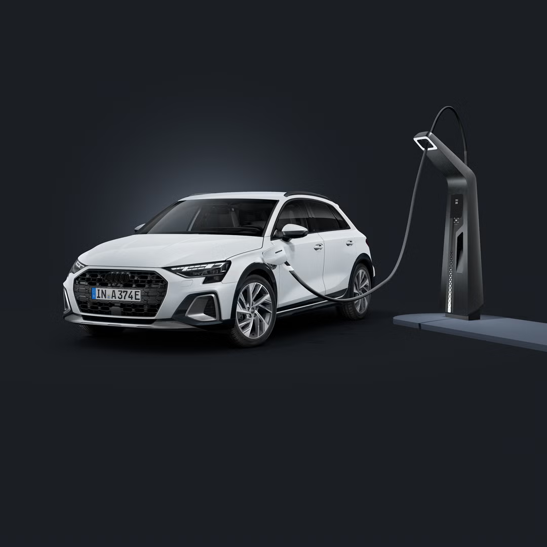 Audi A3 allstreet e-hybrid, prikazan diagonalno od spredaj na temnem ozadju, ob moderni polnilni postaji.