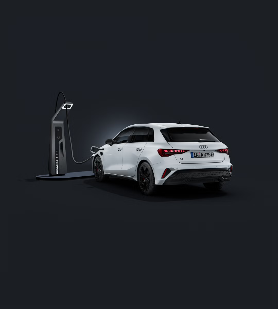Audi A3 Sportback TFSI e, fotografiran iz sprednjega bočnega kota na temnem studijskem ozadju, z LED-žarometi, črnimi športnimi platišči in priključkom za polnjenje na sprednjem levem blatniku.
