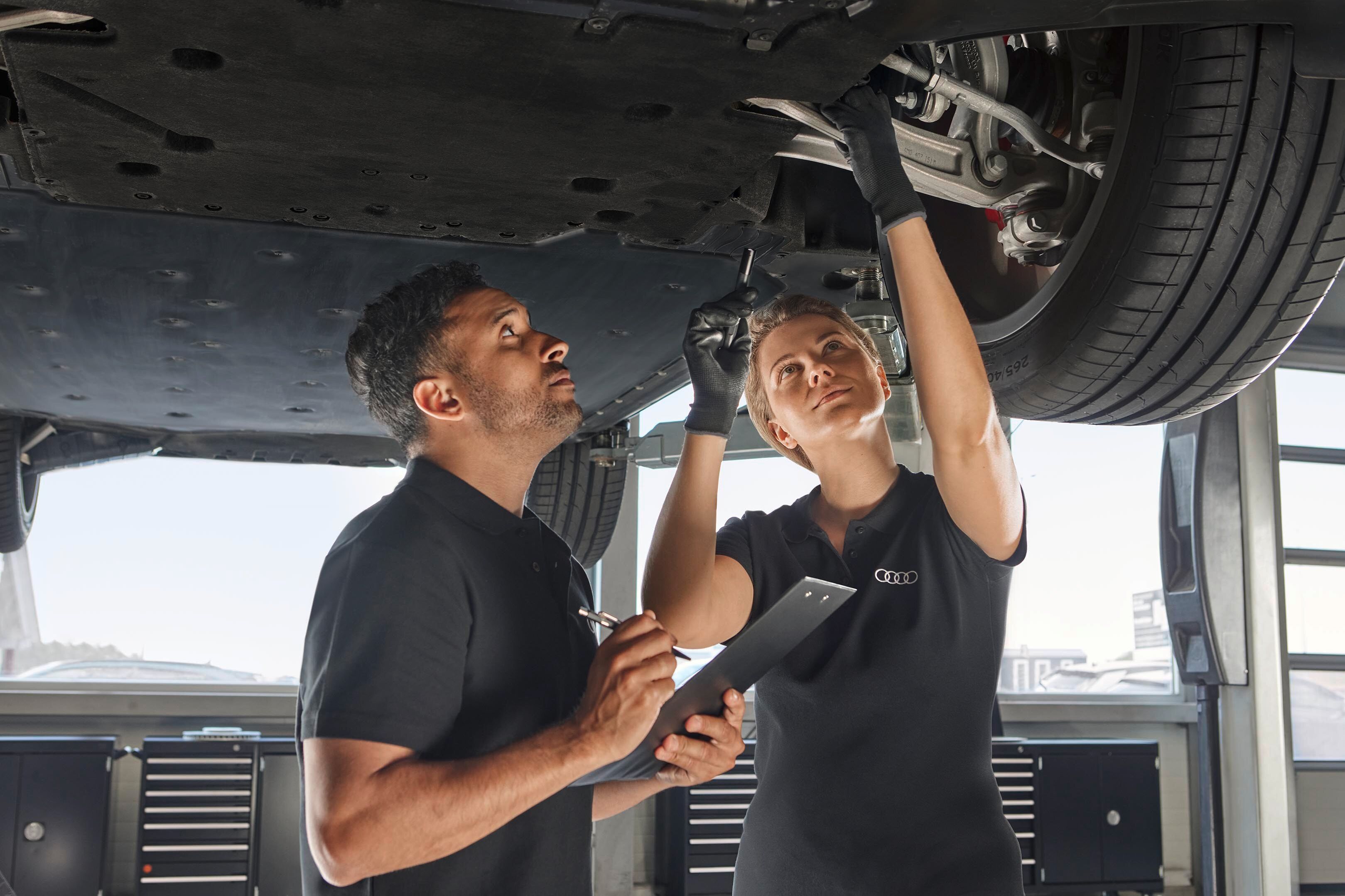 Avtomehanika izvajata pregled podvozja dvignjenega avtomobila